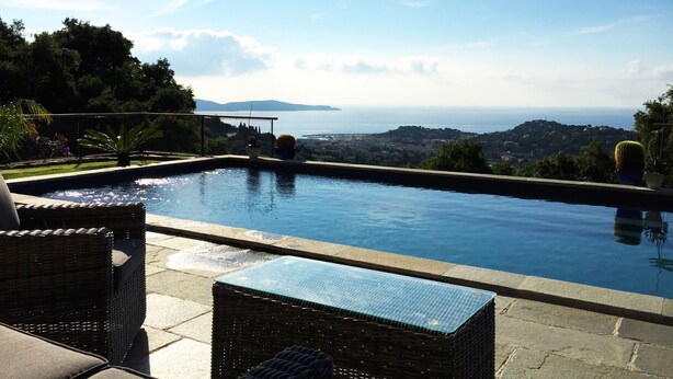 An infinity pool with a view of the sea and mountains, surrounded by wicker furniture and potted plants. - Luxury villa near Saint Tropez, Swimming Pool, Big Garden Super sea view, 220m2 (Cavalaire-Sur-Mer)