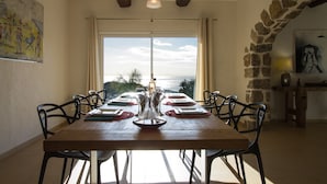 A dining room with a large table set for six, stone walls, and a view through a large window. - Luxury villa near Saint Tropez, Swimming Pool, Big Garden Super sea view, 220m2 (Cavalaire-Sur-Mer)