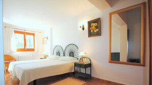 A bedroom with a bed, nightstand, lamp, mirror, and a window with curtains. - Villa Acuarela - 5 beds, 4 bath. Front line villa in Cala d'or. (Cala d´or)