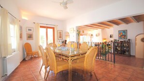 A dining area with a glass table and wicker chairs, a ceiling fan, and a view of the outdoors. - Villa Acuarela - 5 beds, 4 bath. Front line villa in Cala d'or. (Cala d´or)