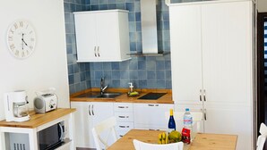 Una cocina compacta con armarios blancos, microondas, tostadora y lavabo.