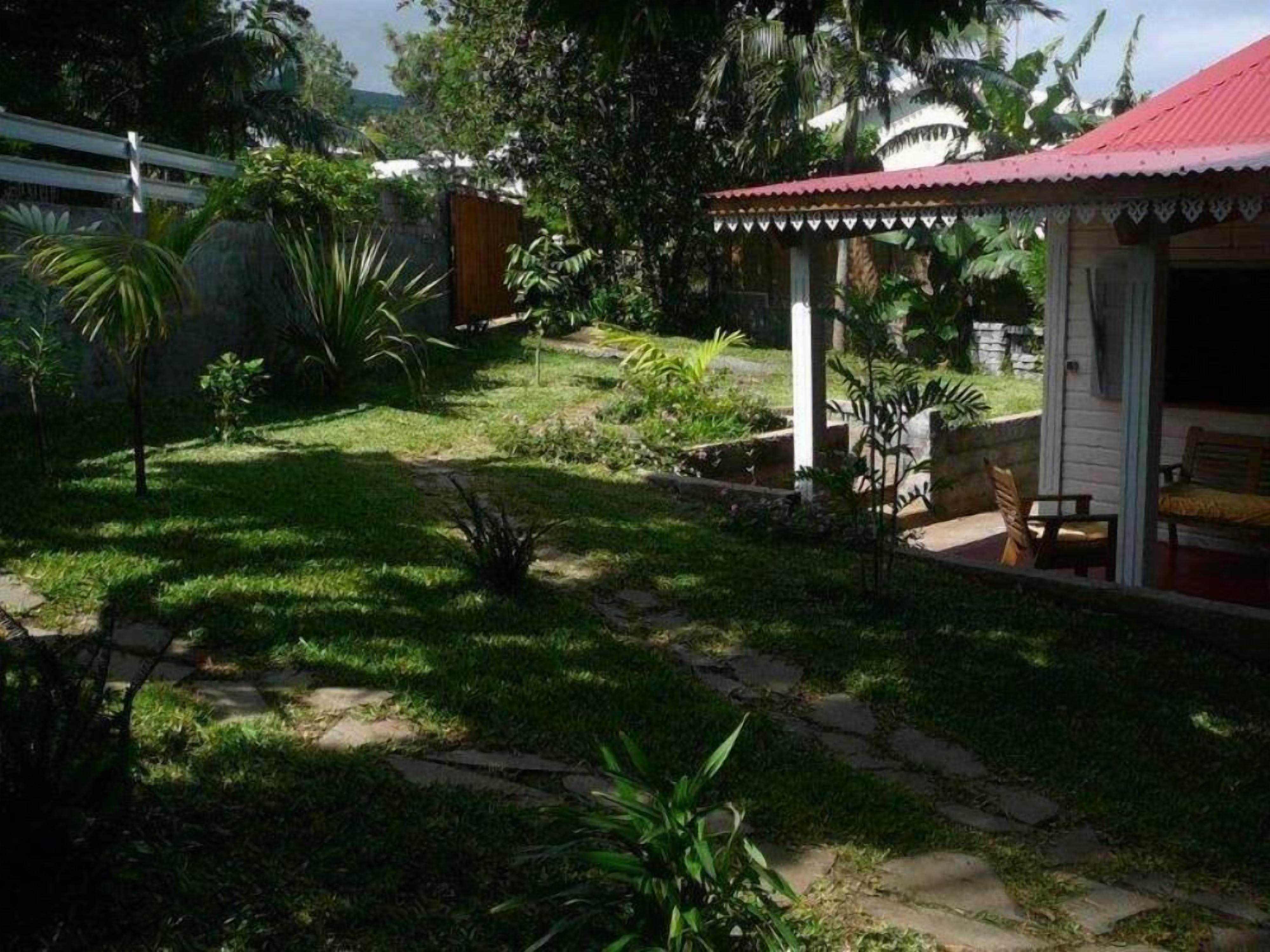 Un giardino con un gazebo, un vialetto e una piccola zona relax con sedie.