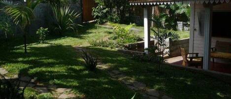 Un giardino con un gazebo, un vialetto e una piccola zona relax con sedie.