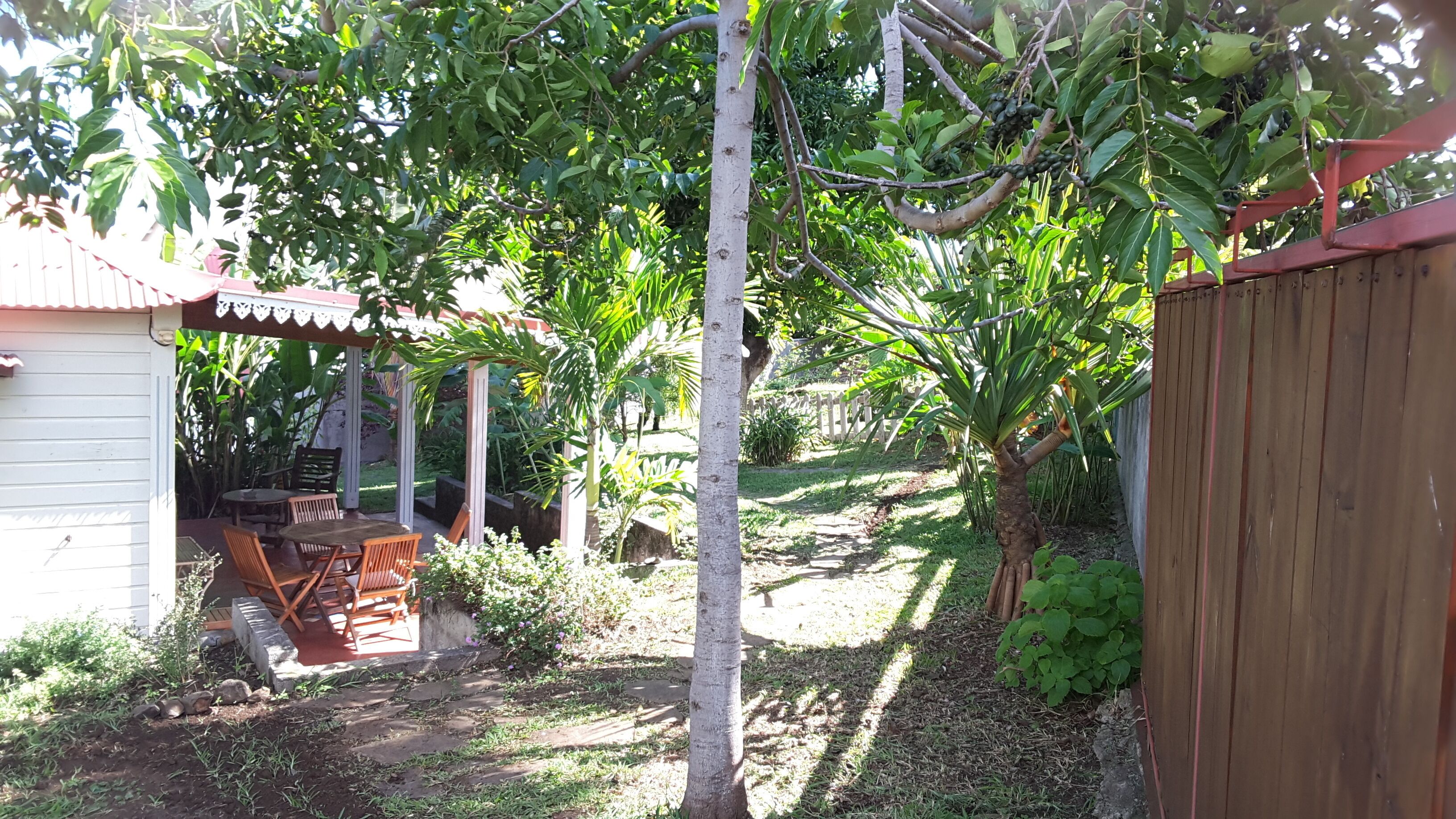 A garden with a wooden table and chairs, a small shed, and a wooden fence.