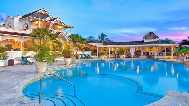 Ein Resort mit einem großen Schwimmbad, Liegestühlen und einem überdachten Bereich mit Blick auf das Schwimmbad.
