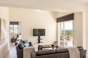 Een moderne woonkamer met een flatscreen televisie, leren banken, een salontafel en een balkon met uitzicht.
