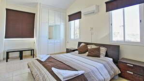 Une chambre à coucher comprenant un lit, un banc, une armoire, une table de chevet et une fenêtre donnant sur un beau paysage.