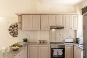 Een keuken met beige kastjes, een magnetron, een broodrooster en een fornuis.