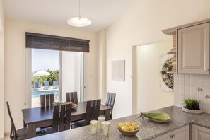 Een moderne keuken met een granieten aanrecht, een eethoek met tafel en stoelen, en uitzicht op een zwembad.