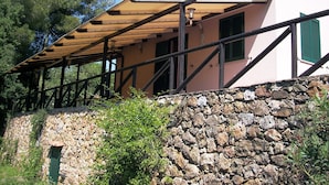 Un mur de pedra amb una estructura de pergola de fusta.