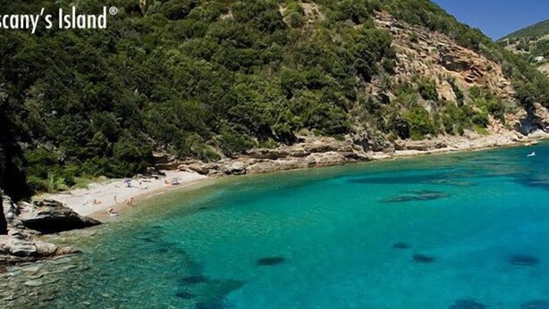 Una zona costanera amb aigües turqueses cristal·lines, penya-segats rocosos i un vaixell foncat a prop de la riba.