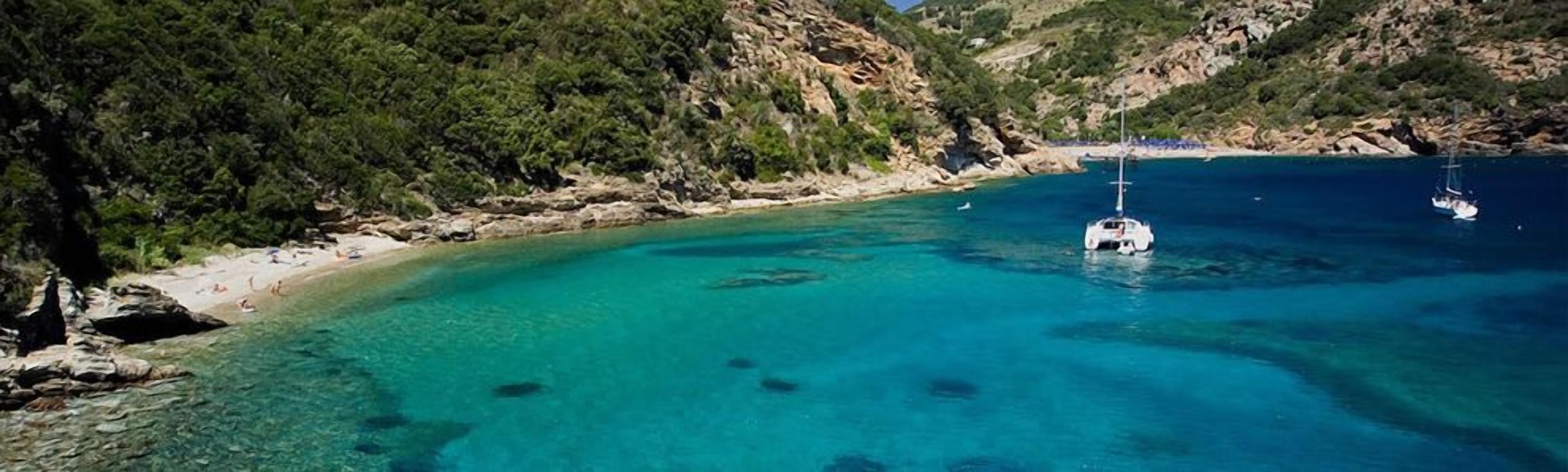A coastal area with clear turquoise waters, rocky cliffs, and a boat anchored near the shore.