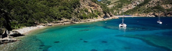 A coastal area with clear turquoise waters, rocky cliffs, and a boat anchored near the shore. - Apartment/ flat - Rio marina (Isola d'Elba)