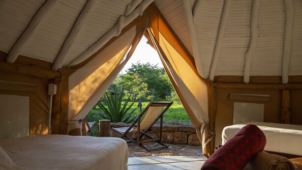 A cozy tented accommodation with two beds, a chair, and a view of greenery outside. - Nativo Glamping (Barichara)