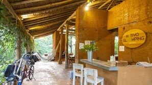 A rustic bar area with a hammock and bicycles, a brick wall, and a sign reading "Nativo Glamping Barichara". - Nativo Glamping (Barichara)