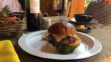 A dining table with a plate of food, a bottle of wine, and a glass of wine.