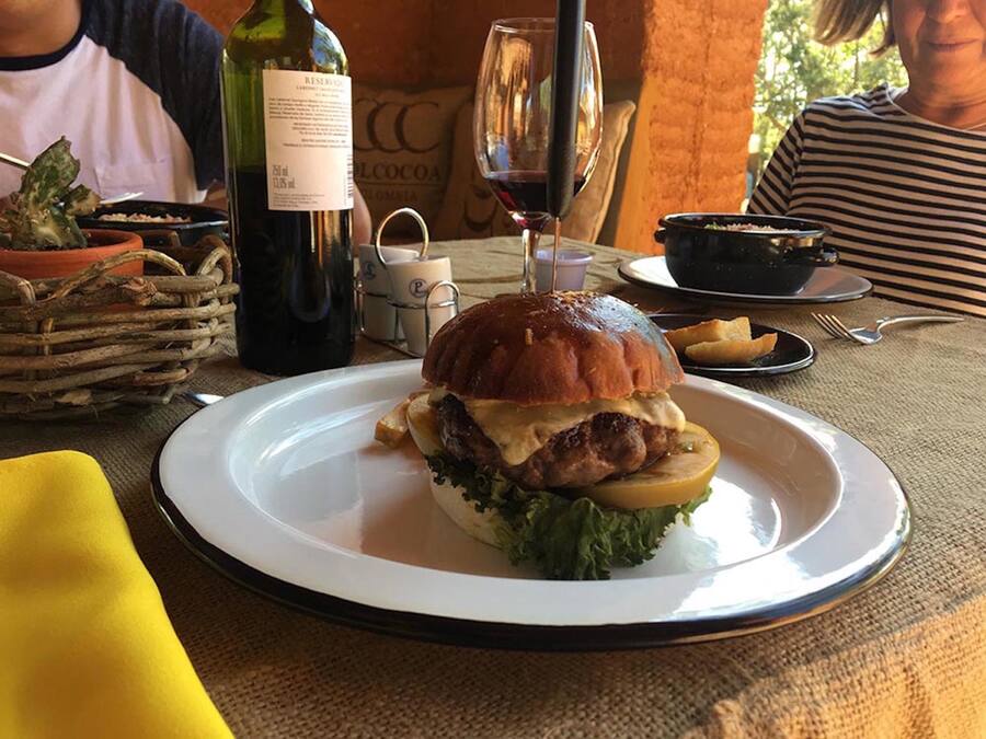 A dining table with a plate of food, a bottle of wine, and a glass of wine.