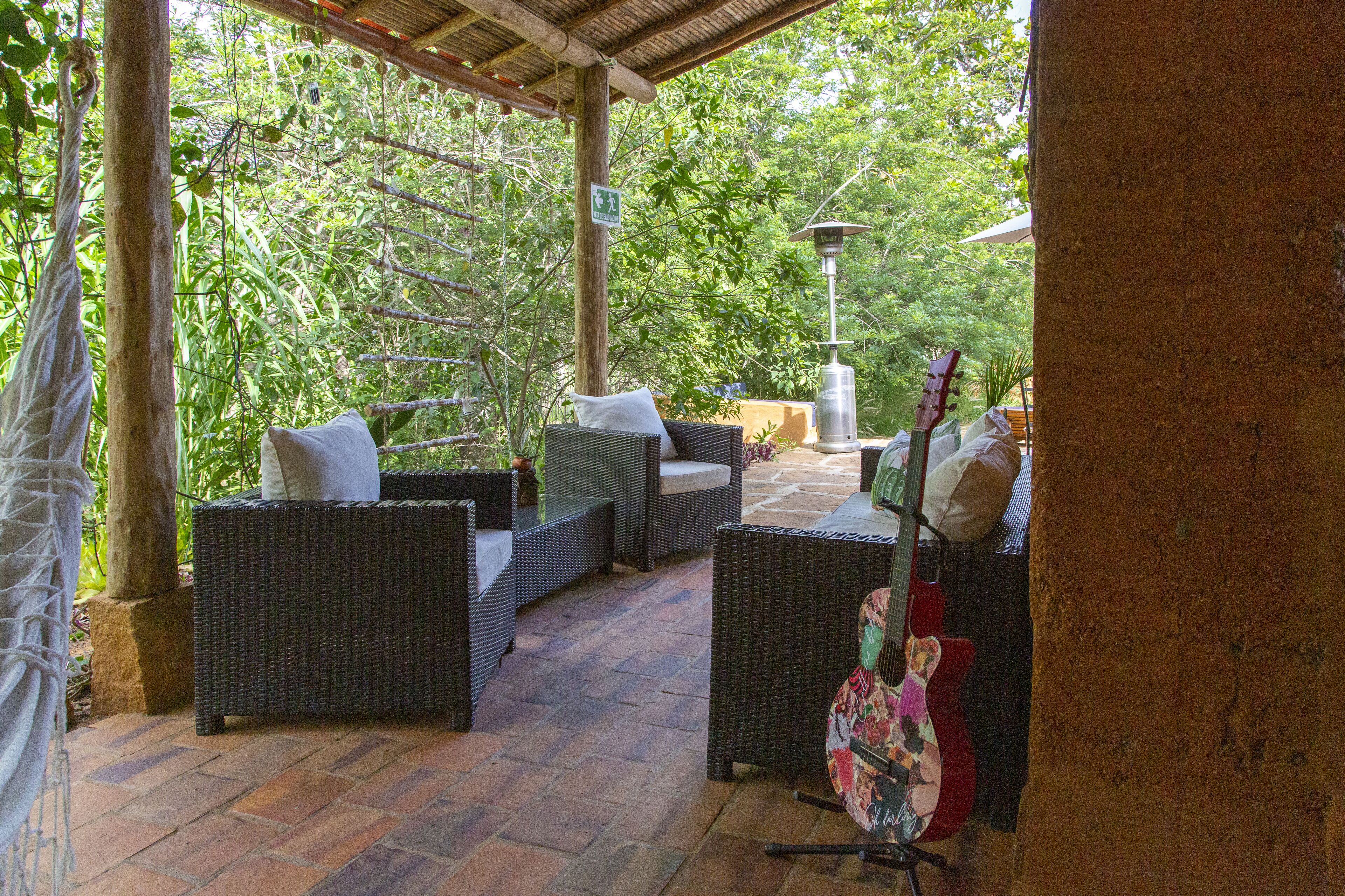 Un patio al aire libre con mobiliario de mimbre, una guitarra y una lámpara.