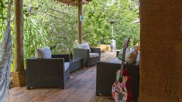 Un patio al aire libre con mobiliario de mimbre, una guitarra y una lámpara.