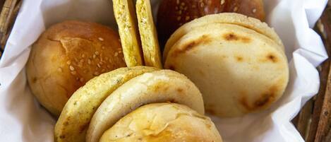 Una cesta con diversos tipos de panecillos, algunos con semillas de sésamo y otros con diferentes ingredientes.