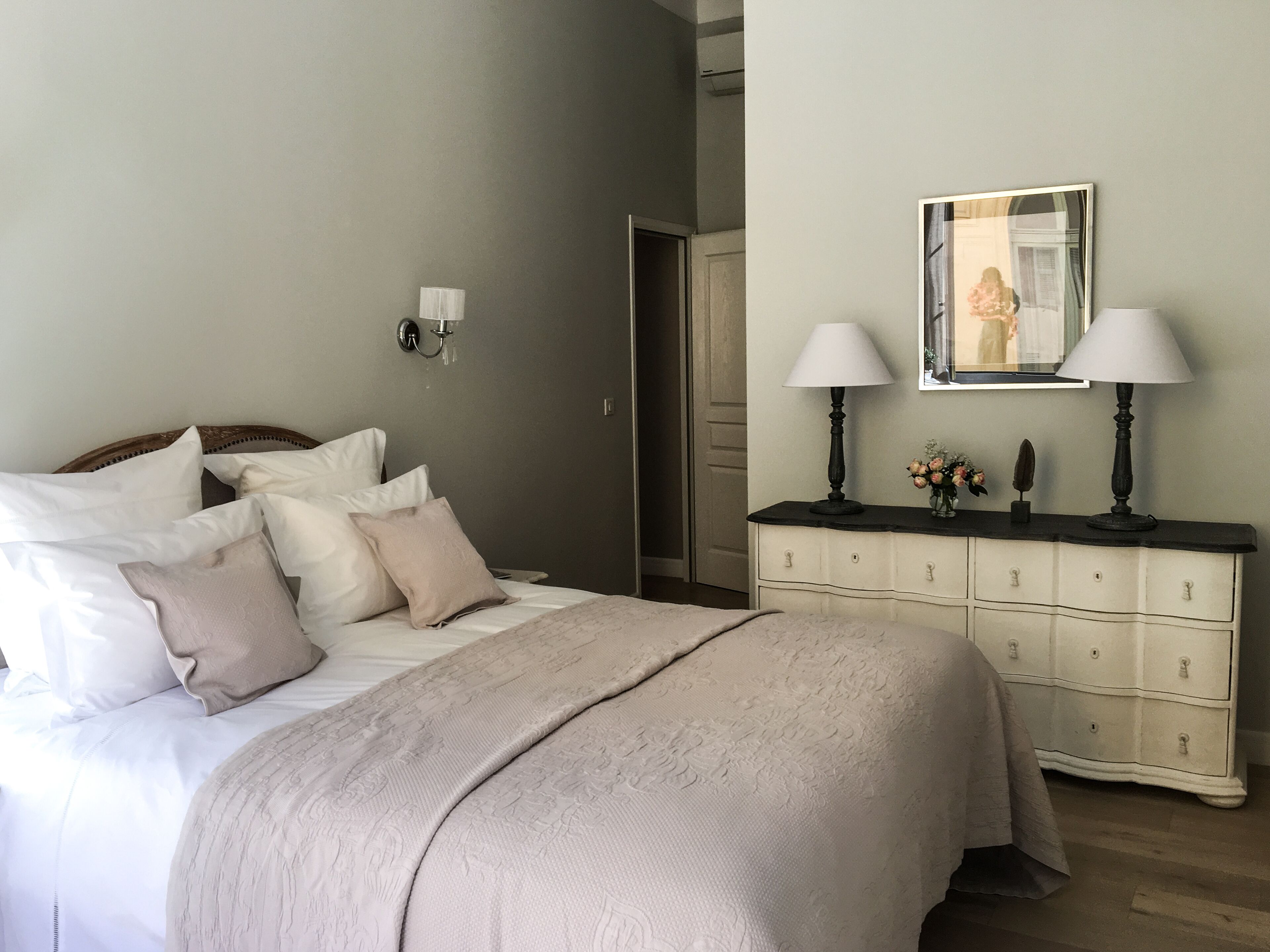 A bedroom with a bed, bedside lamps, a dresser, and a mirror.