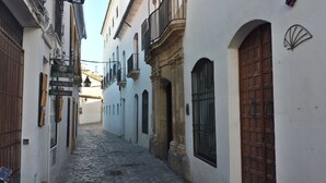 Una estrecha calle adoquinada flanqueada por edificios blancos con puertas y ventanas de madera.