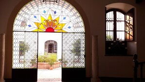 Una habitación con un amplio ventanal de vidrio emplomado, una puerta de madera y vistas al jardín exterior.