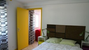 A bedroom with a bed, a nightstand with a lamp, a window with curtains, and a door. -  COUNTRYSIDE AIR-CONDITIONED COTTAGE, PRIVATE POOL  NEAR BANDOL SANARY CASSIS (Évenos)