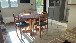 A cozy room with a wooden dining table, chairs, a sofa, and a TV on the wall. -  COUNTRYSIDE AIR-CONDITIONED COTTAGE, PRIVATE POOL  NEAR BANDOL SANARY CASSIS (Évenos)