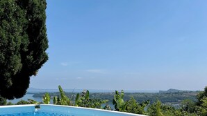 A clear blue swimming pool with a view of a distant landscape and a large tree. - Your country Villa with a amazing view, private garden and private pool! (salò (bs))