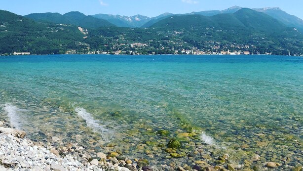 A clear lake with a rocky shoreline and a town across the water. - Your country Villa with a amazing view, private garden and private pool! (salò (bs))