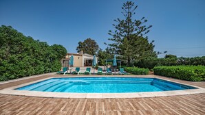 A rectangular swimming pool with a wooden deck, surrounded by green hedges and trees. - HOUSE IN THE AREA OF CALA BONA WITH POOL AND GARDEN (CALA BONA)