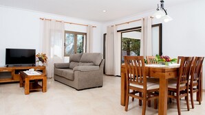 A living room with a sofa, TV, wooden coffee table, and dining area with a table and chairs. - HOUSE IN THE AREA OF CALA BONA WITH POOL AND GARDEN (CALA BONA)
