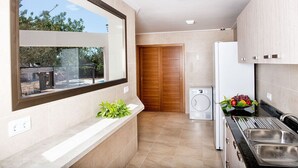 A modern kitchen with a built-in oven, a sink, and a window overlooking a garden. - HOUSE IN THE AREA OF CALA BONA WITH POOL AND GARDEN (CALA BONA)
