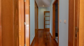 A hallway with wooden doors, a glass door, and a wooden ladder against the wall.