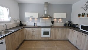 Une cuisine moderne avec des meubles en bois, une hotte en acier inoxydable et des appareils électroménagers intégrés.