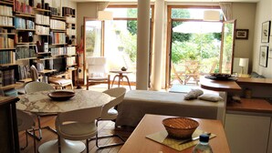 Ein gemütliches Wohnzimmer mit Essbereich, einer Bücherwand und Blick auf den Garten.