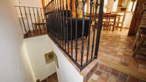 A staircase with a black metal railing leading to a room with a bed and a dining table. - Rural house Nº13 Molino Jaraiz for 8 people (Yeste)