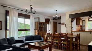 A living room with a sofa, a wooden coffee table, a dining area with a table and chairs, and a kitchen area with cabinets and a counter. - Rural house Nº13 Molino Jaraiz for 8 people (Yeste)