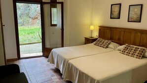 A hotel room with two beds, a wooden headboard, a nightstand with a lamp, and a door leading to a balcony. - Rural house Nº13 Molino Jaraiz for 8 people (Yeste)