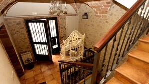 A staircase with a wrought iron railing, a white ornate chair, and a black door with barred windows. - 800 Square Meter Unique Property On Costa Brava (Sant Mori)