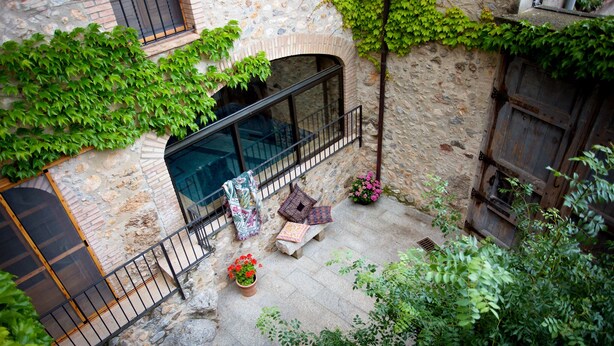 A stone building with a balcony, potted plants, and a wooden door. - 800 Square Meter Unique Property On Costa Brava (Sant Mori)