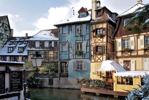 A row of traditional European buildings with snow on the roofs, a canal in the foreground, and a small boat docked at the edge. - Apartment/ flat - COLMAR (Colmar)