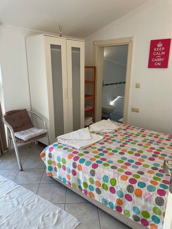 A bedroom with a bed, a chair, a wardrobe, and a bathroom visible through an open door. - Poseidon 3, seafront 3 bedroom apartment with unobstructed beach and sea views. (Calis Plaji)