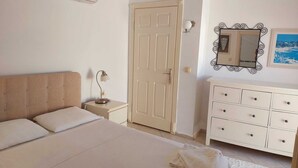 A bedroom with a bed, bedside table, dresser, and a door. - Poseidon 3, seafront 3 bedroom apartment with unobstructed beach and sea views. (Calis Plaji)
