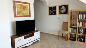 A living room with a TV, a bookshelf, and two framed pictures on the wall.