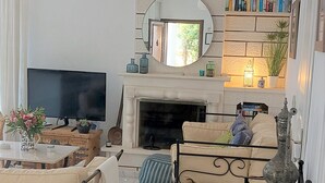 Un salon avec une cheminée, un téléviseur et une bibliothèque.