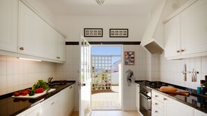 Una cocina con armarios blancos, encimera negra y vistas al exterior.