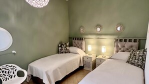 Un dormitorio con dos camas individuales, una mesita redonda pequeña y una lámpara colgante.