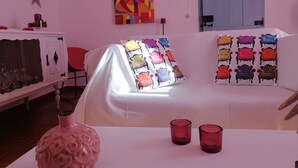 A room with a white sofa, colorful cushions, a decorative vase, and a painting on the wall. - Monte da Rua 13 - Casa de Aldeia (Redondo)